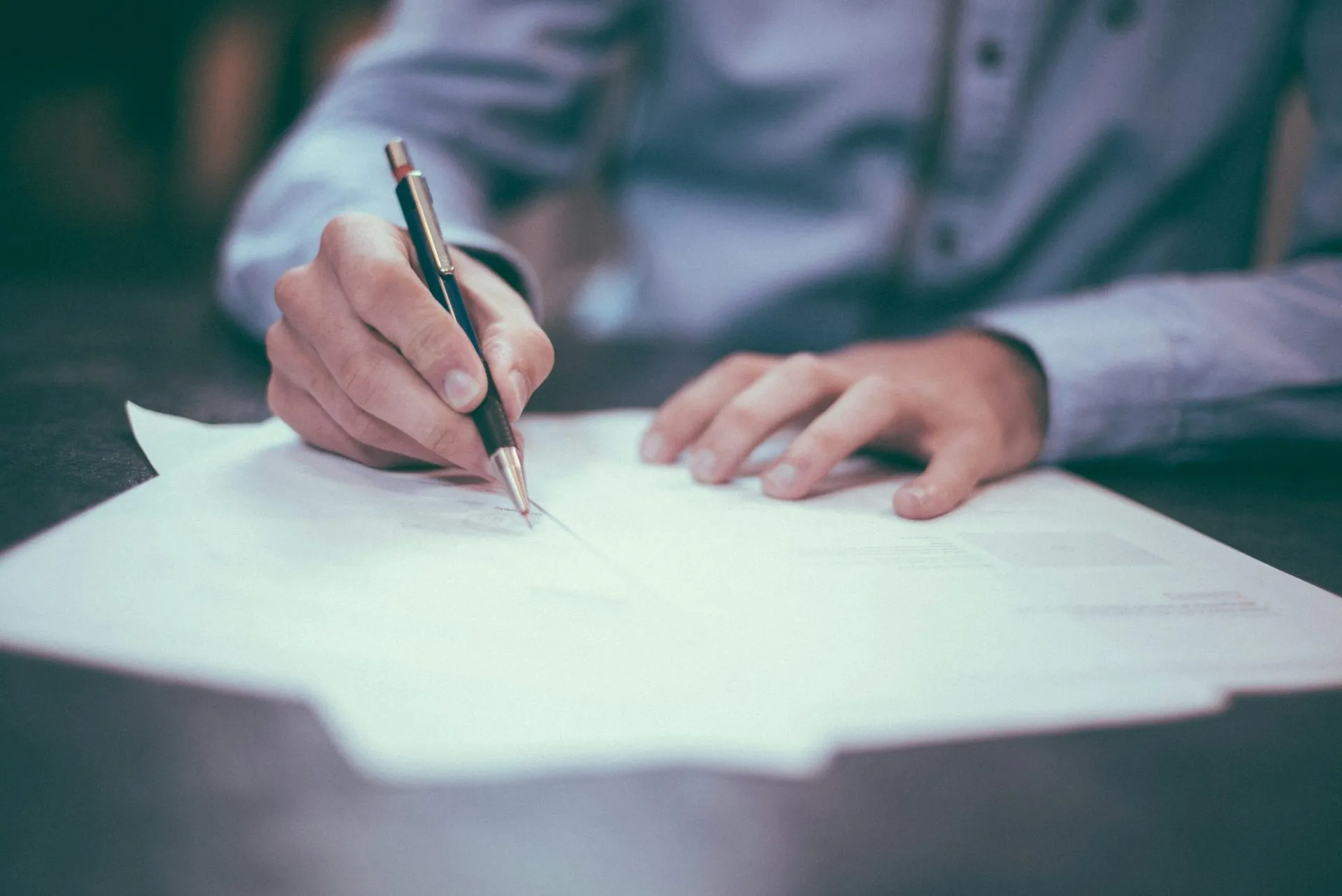 Intestazioni e accessi vanno scritti nel contratto, non lasciati alla fiducia Uomo che firma un documento con una penna su una scrivania